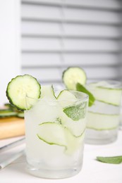 Photo of Tasty fresh cucumber water with mint on white wooden table