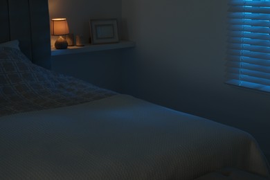 Large bed and shelf with accessories in stylish bedroom at night