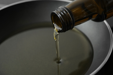 Pouring cooking oil from bottle into frying pan, closeup