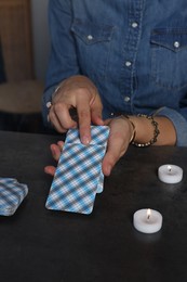 Photo of Fortune teller with deck of tarot cards at grey table indoors, closeup