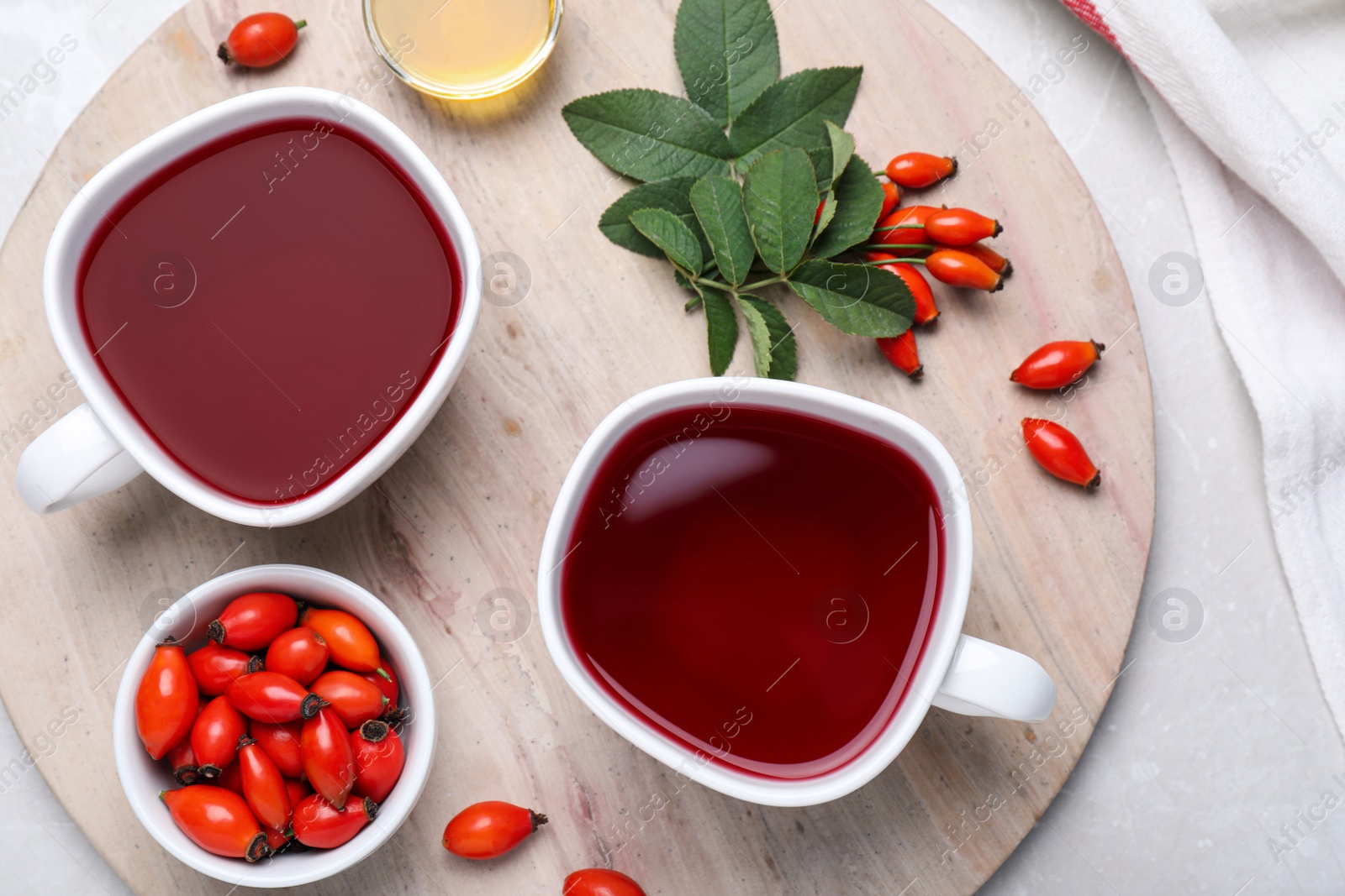 Photo of Fresh rose hip tea and berries on light table, flat lay