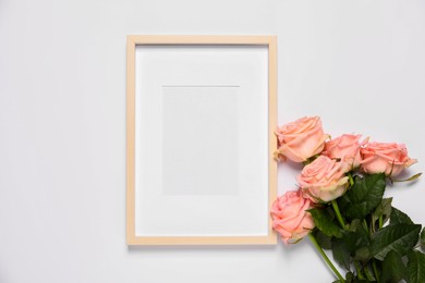 Photo of Empty photo frame and beautiful flowers on white background, top view. Space for design
