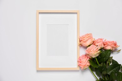 Empty photo frame and beautiful flowers on white background, top view. Space for design