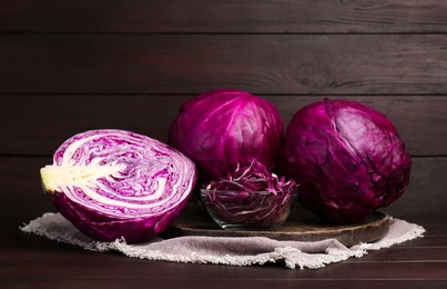 Photo of Whole and cut ripe red cabbages on wooden table