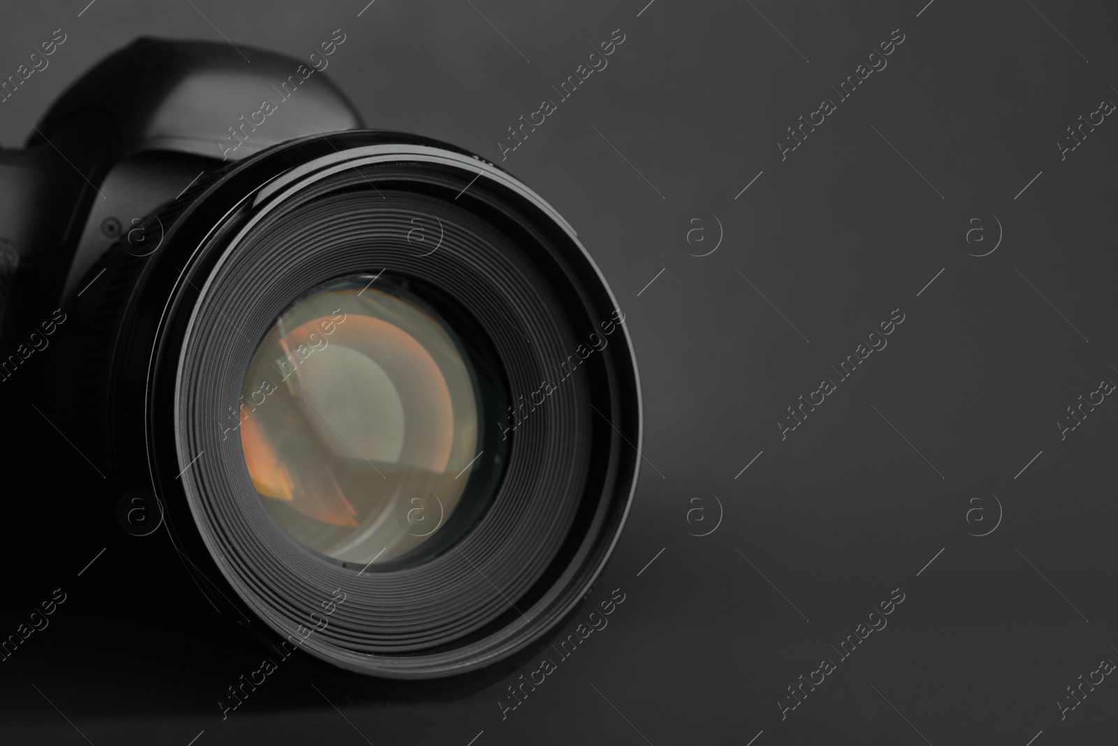 Photo of Modern camera with lens on black background, closeup. Space for text