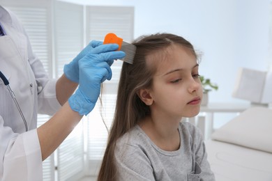 Photo of Doctor using nit comb on girl's hair in clinic. Anti lice treatment