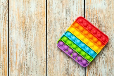 Rainbow pop it fidget toy on light wooden table, top view. Space for text