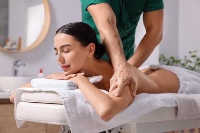 Woman receiving professional massage on couch in spa salon