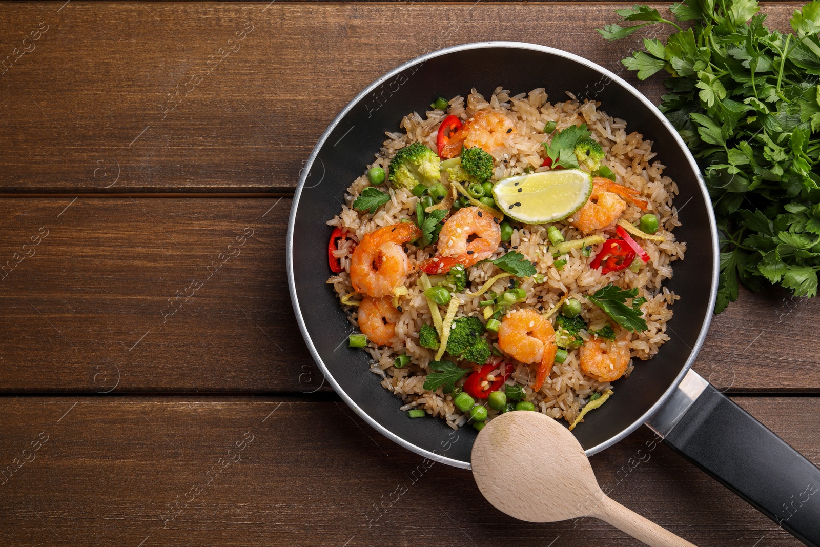Photo of Tasty rice with shrimps and vegetables served on wooden table, flat lay. Space for text