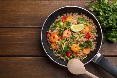 Tasty rice with shrimps and vegetables served on wooden table, flat lay. Space for text