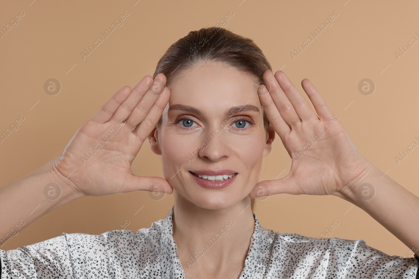 Photo of Woman massaging her face on beige background