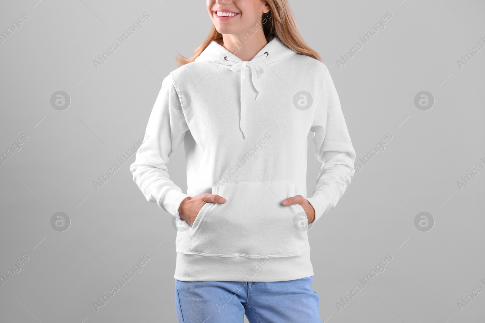 Photo of Woman in hoodie sweater on light background. Space for design