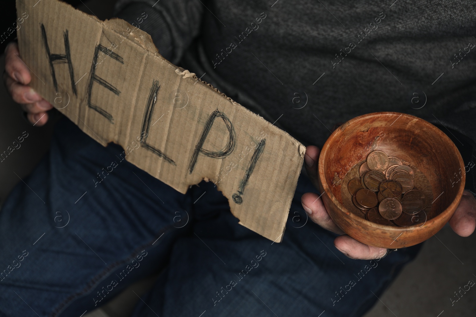 Photo of Poor homeless man with help sign holding bowl of donations, closeup