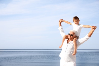 Photo of Cute little boy with grandfather spending time together near sea