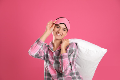 Beautiful woman with pillow on pink background. Bedtime