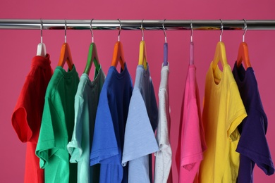 Photo of Rack with stylish children clothes on pink background, closeup