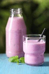Photo of Delicious blackberry smoothie and mint on light blue wooden table, closeup