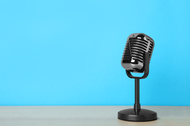 Photo of Retro microphone on wooden table against light blue background, space for text. Interview