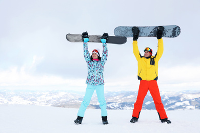 Photo of Lovely couple with snowboards on hill. Winter vacation