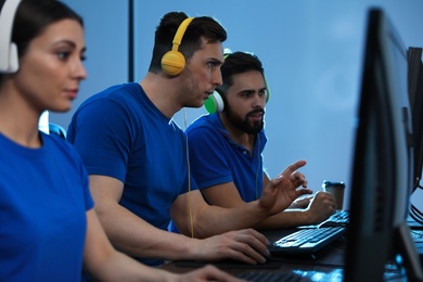 Photo of Young people playing video games on computers indoors. Esports tournament