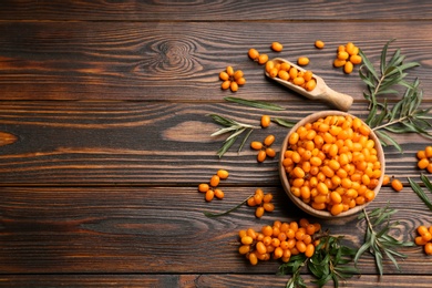 Photo of Fresh ripe sea buckthorn on wooden table, flat lay. Space for text