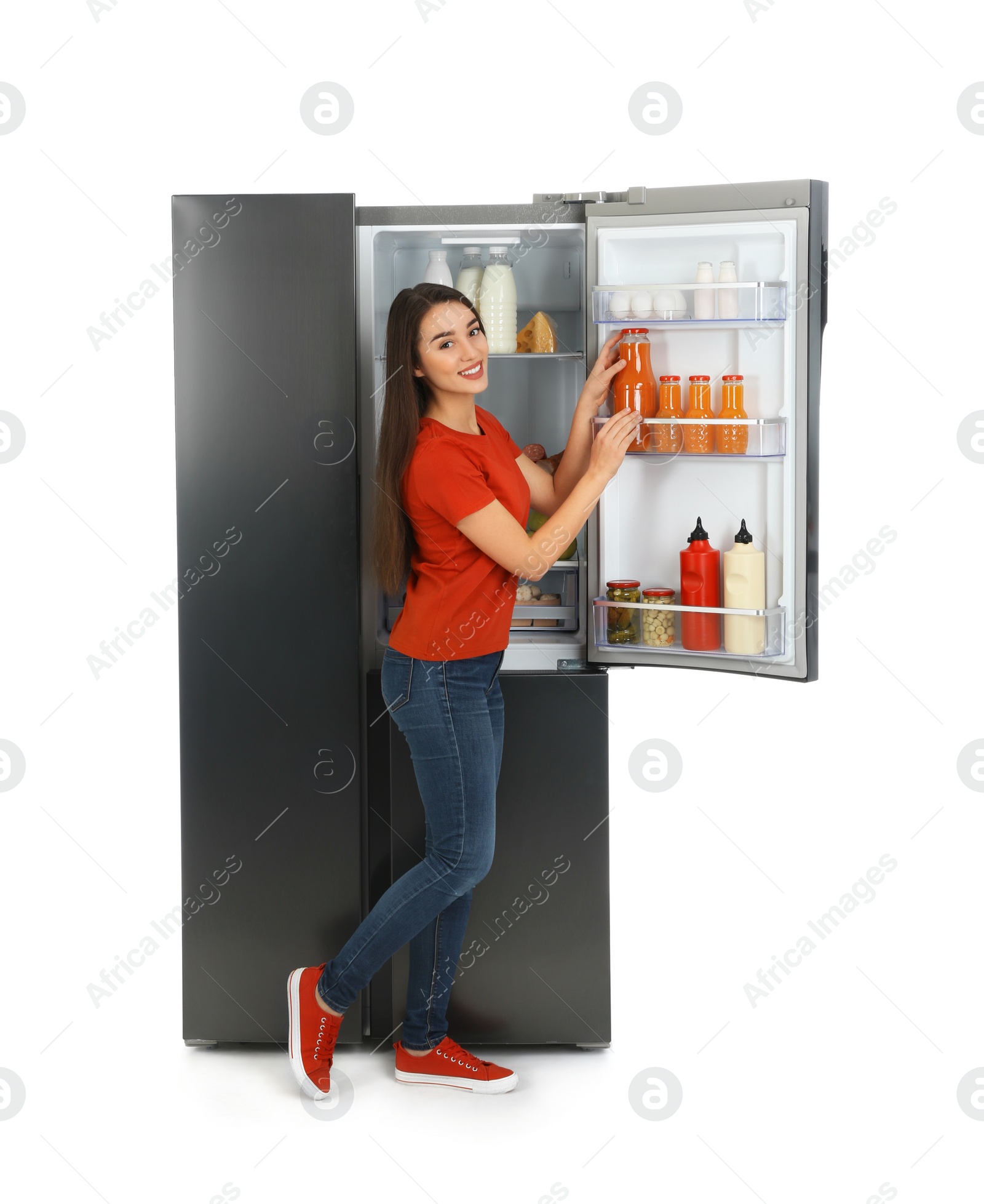 Photo of Young woman taking juice out of refrigerator on white background