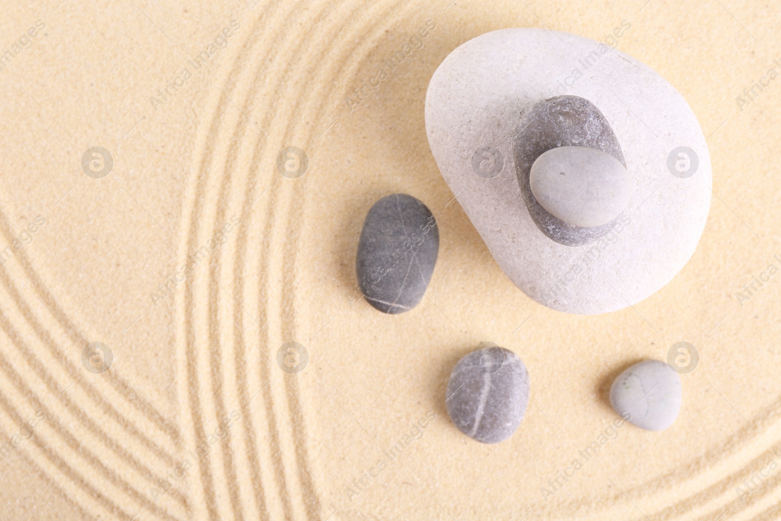 Photo of Zen garden stones on sand with pattern, flat lay. Space for text