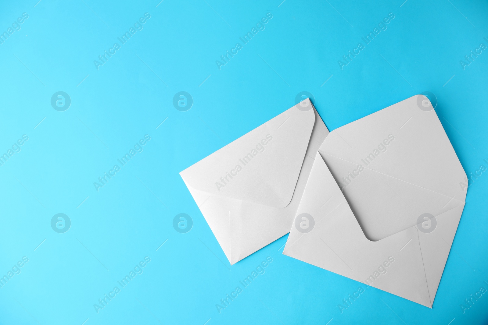 Photo of White paper envelopes on light blue background, flat lay. Space for text