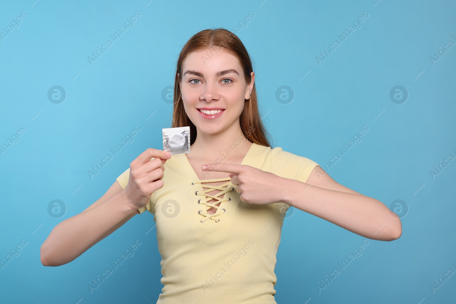 Photo of Woman holding condom on turquoise background. Safe sex