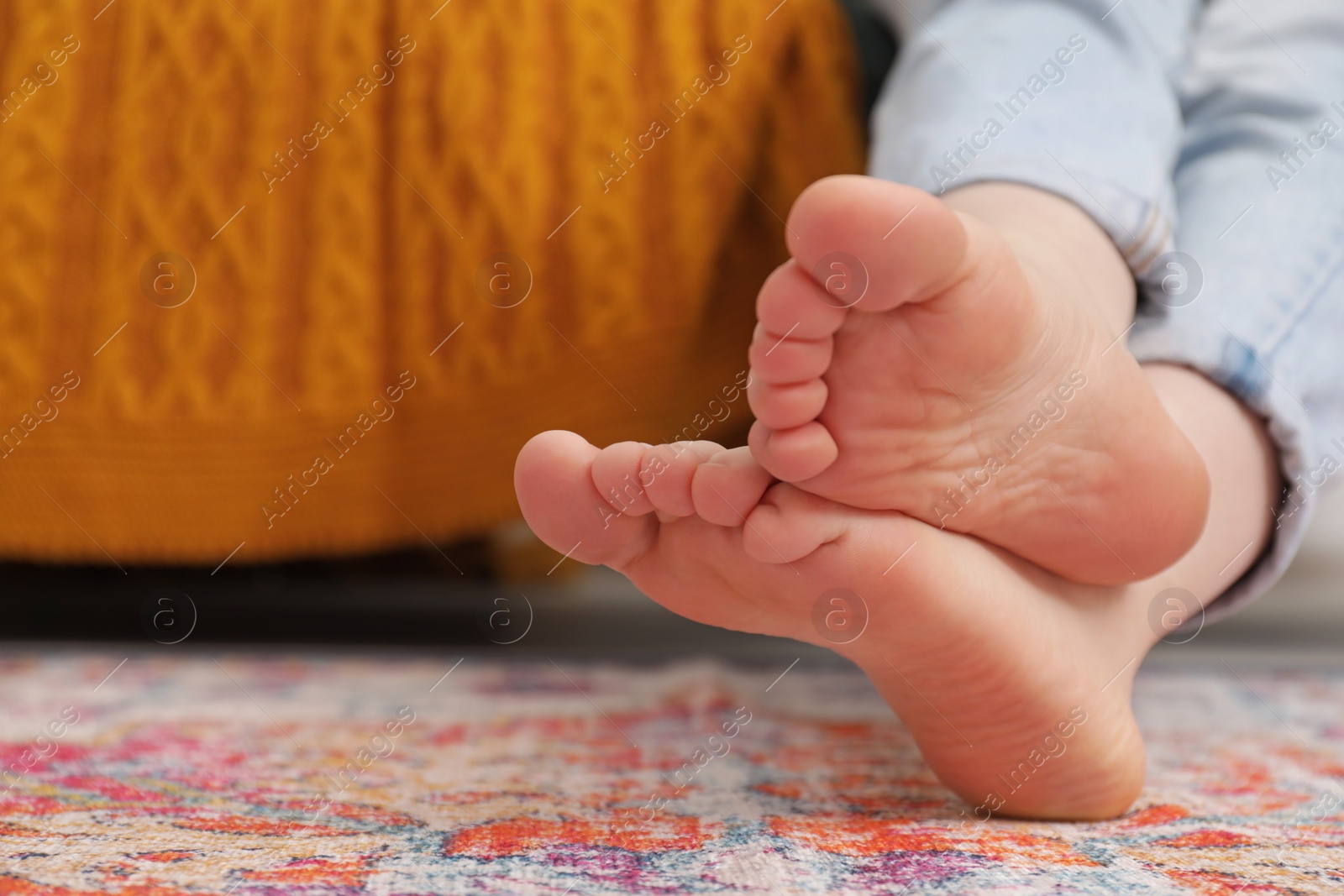 Photo of Woman sitting near carpet with pattern indoors, closeup. Space for text