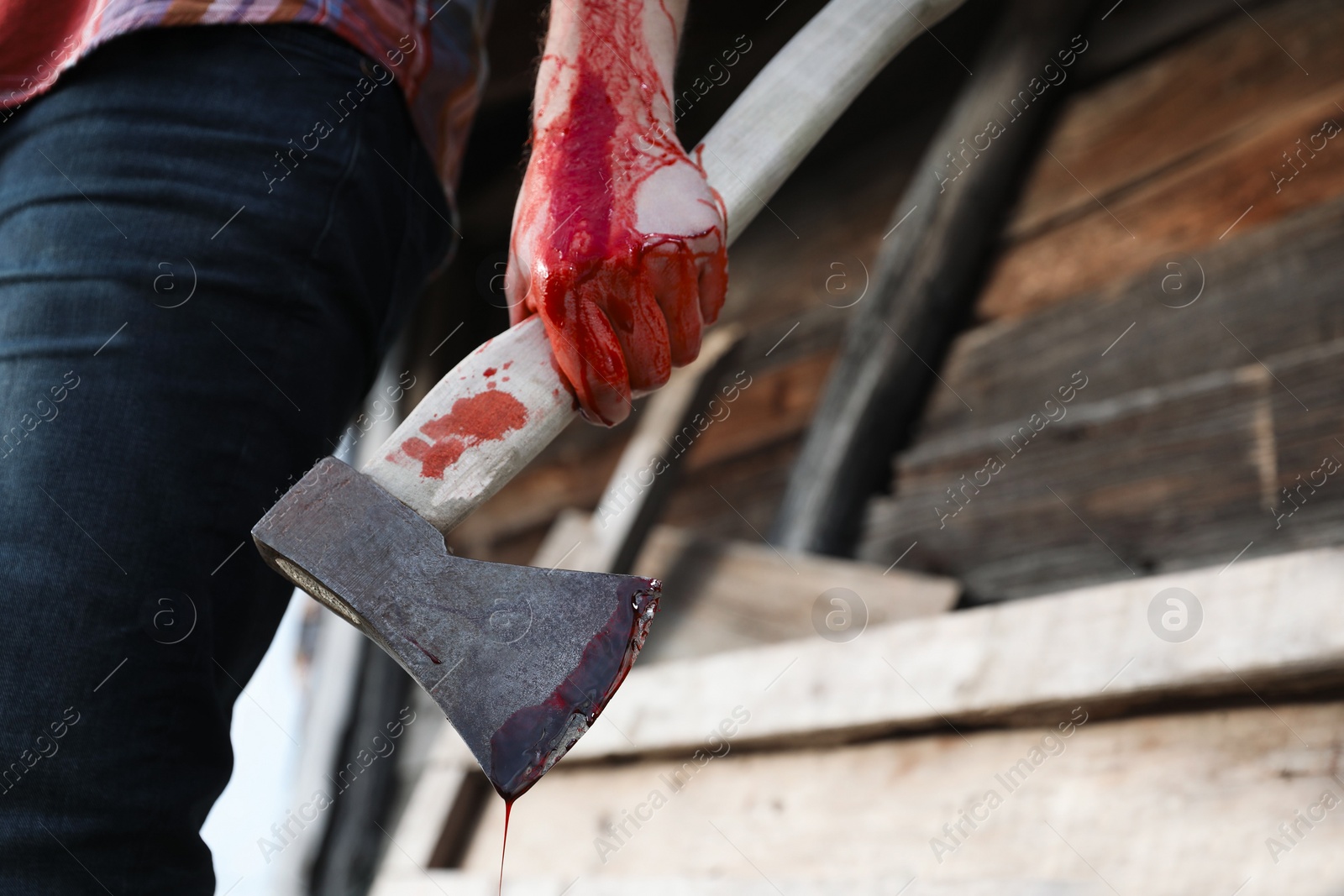 Photo of Man holding bloody axe outdoors, closeup. Space for text