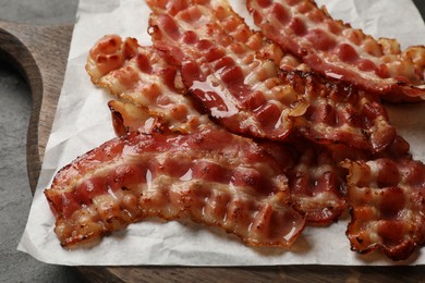 Photo of Board with fried bacon slices on dark table, closeup