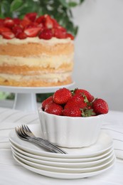 Ripe strawberries and tasty cake with fresh berries on white table, selective focus