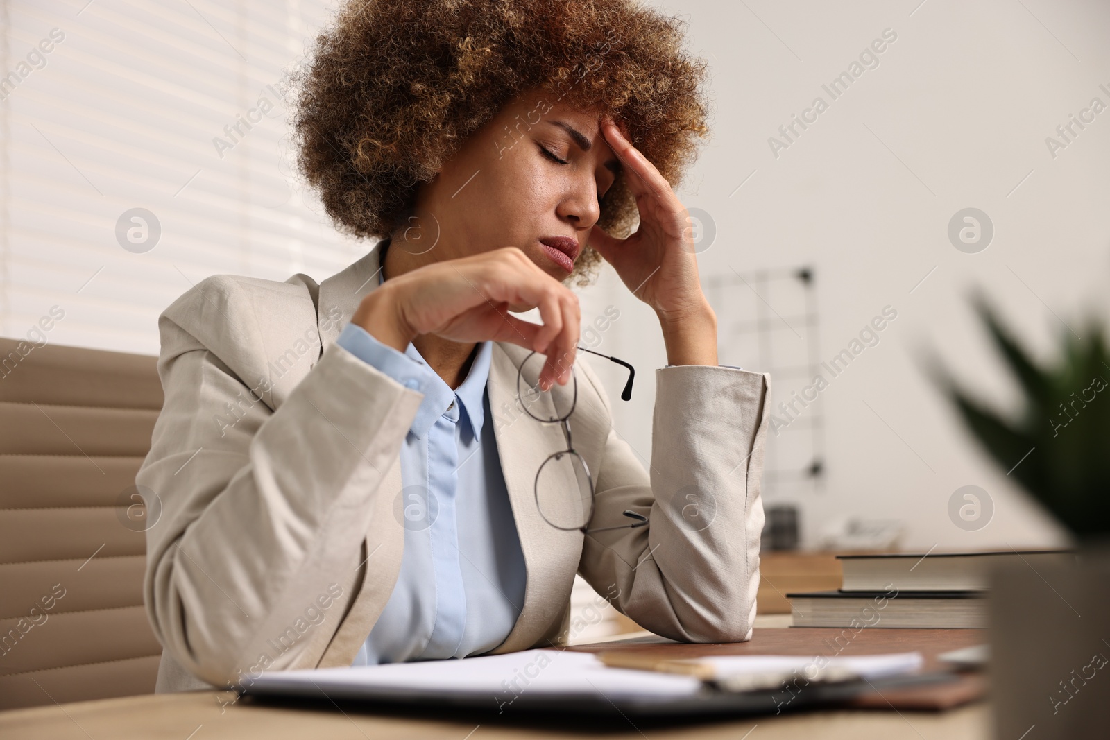 Photo of Woman suffering from headache at workplace in office