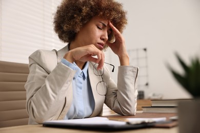 Woman suffering from headache at workplace in office