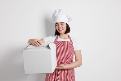 Photo of Happy confectioner with cake box on light grey background