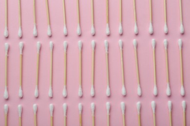 Many wooden cotton buds on pink background, flat lay