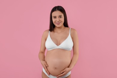 Photo of Happy pregnant woman in stylish comfortable underwear on pink background
