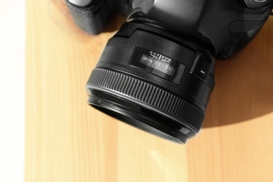 Photo of Professional camera on wooden table, top view. Photographer's equipment