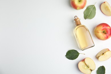 Photo of Natural apple vinegar and fresh fruits on white background, top view. Space for text