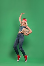 Photo of Happy hippie woman with retro radio receiver dancing on green background