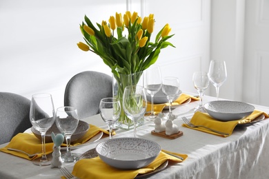 Photo of Beautiful Easter table setting with yellow tulips indoors