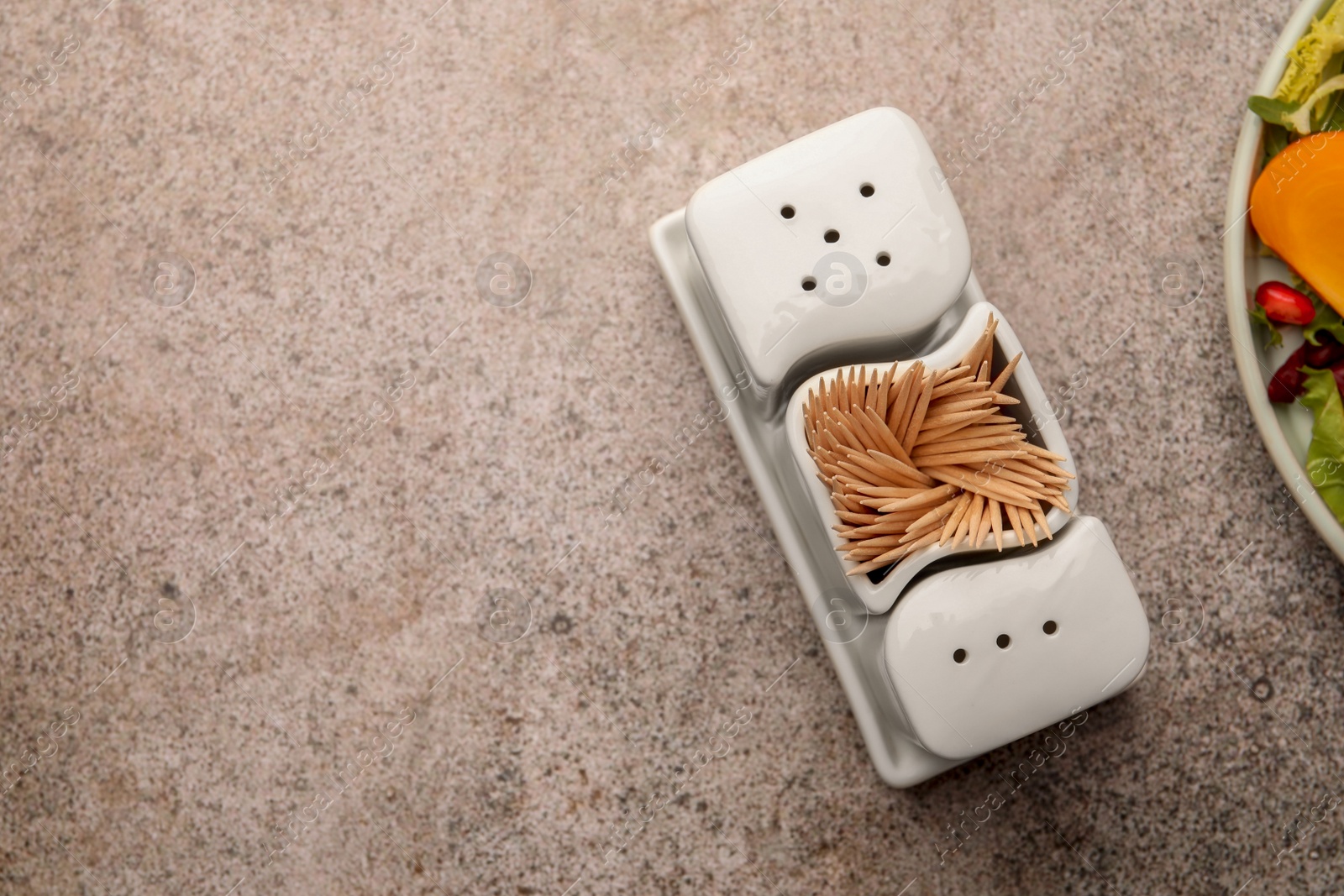 Photo of Holder with salt, pepper and toothpicks near food on grey table, flat lay. Space for text