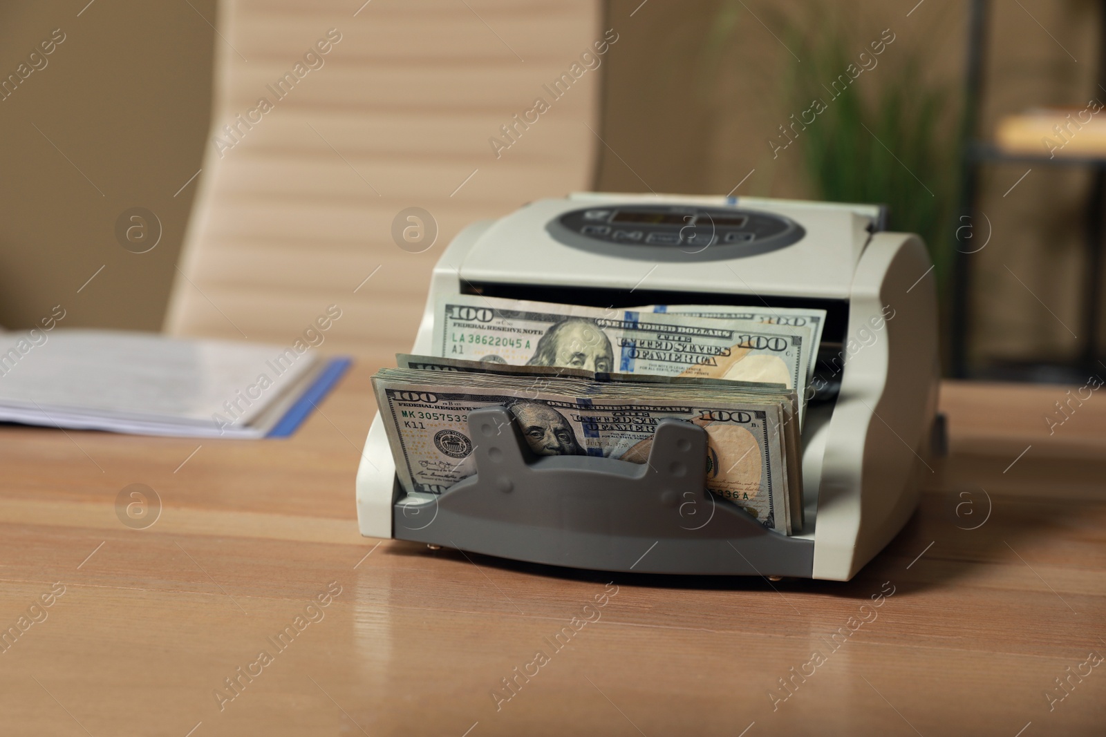 Photo of Modern banknote counter with money on wooden table indoors