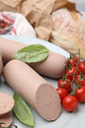 Photo of Delicious liver sausages and cherry tomatoes on light grey table, closeup