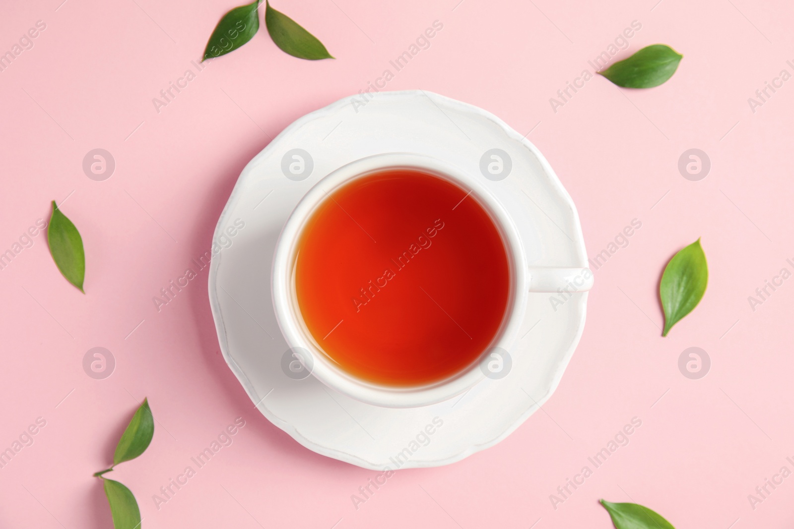 Photo of Cup of delicious tea with green leaves on color background, top view