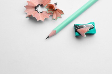 Photo of Pencil, sharpener and shavings on white background, flat lay. Space for text