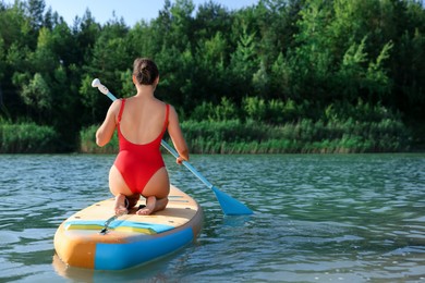 Woman paddle boarding on SUP board in river, back view