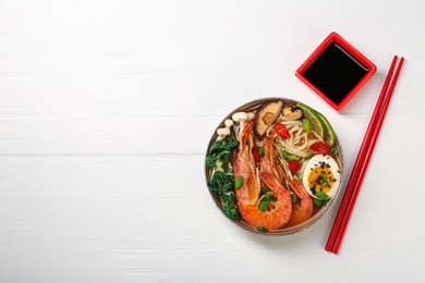 Photo of Delicious ramen with shrimps and egg in bowl served on white wooden table, flat lay and space for text. Noodle soup