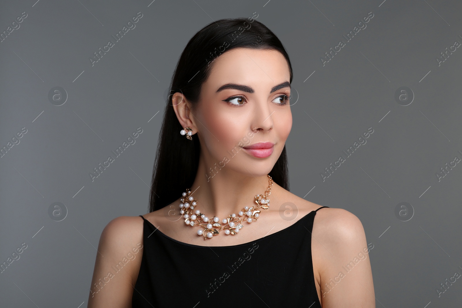 Photo of Beautiful young woman with elegant jewelry on dark grey background